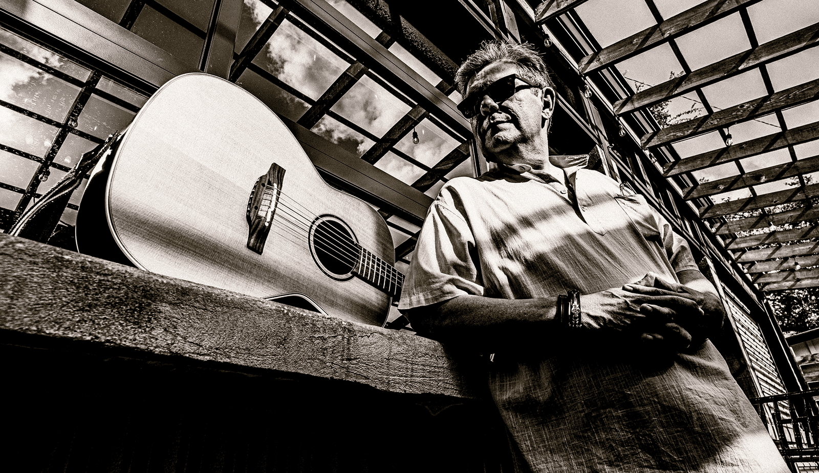 A dramatic black and white photo of Blacky V and his trusty classical guitar.