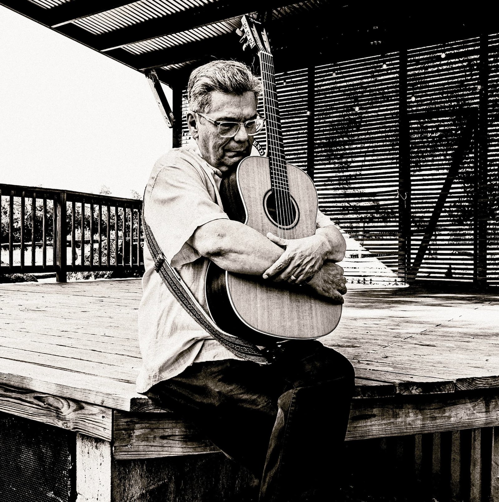 A black and white photo of Blacky V hugging his guitar